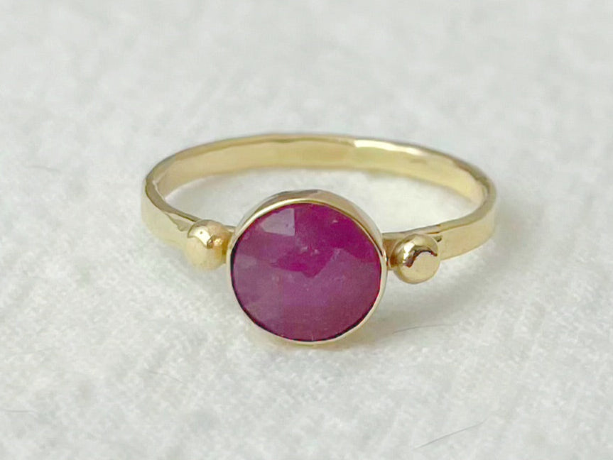 Gold ring with a pink gemstone on a white textured background