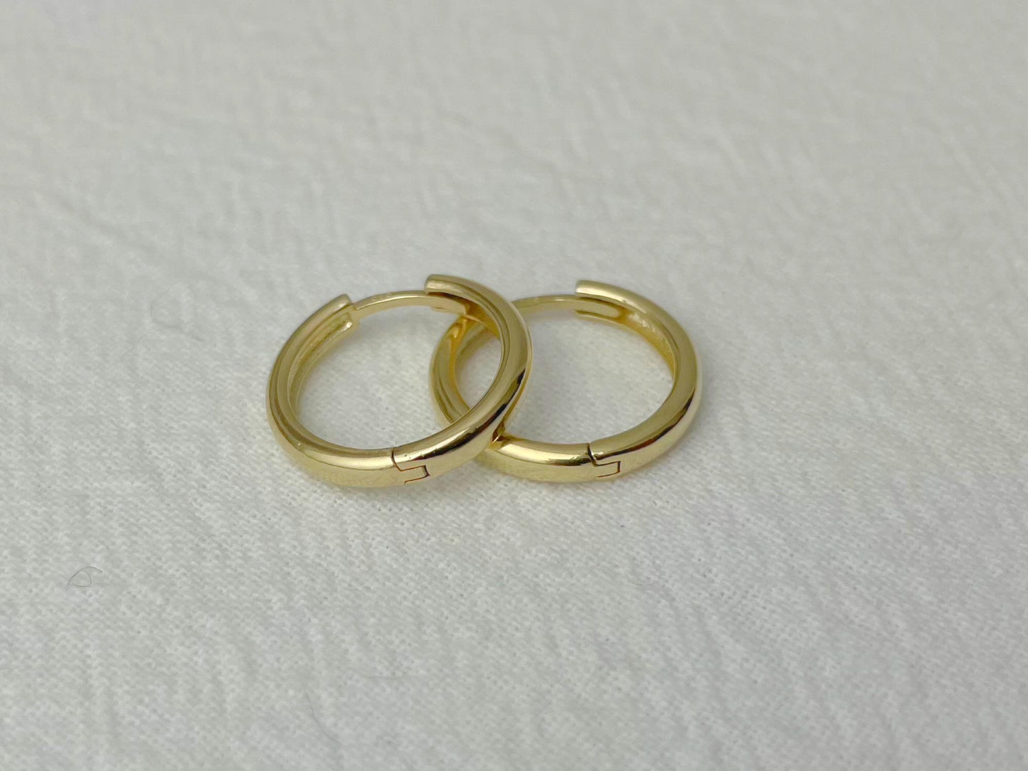 Elegant 14k gold huggies with a high-polish surface and seamless clasp mechanism