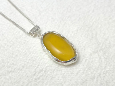 Yellow stone pendant on a silver chain against a white background