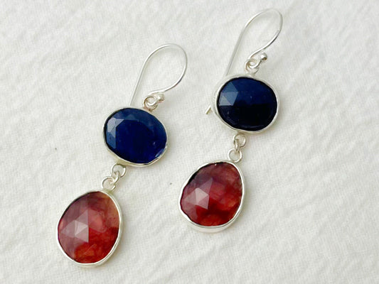 Pair of earrings with blue and red stones on a white background