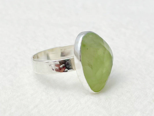 Silver ring with a green stone on a white background
