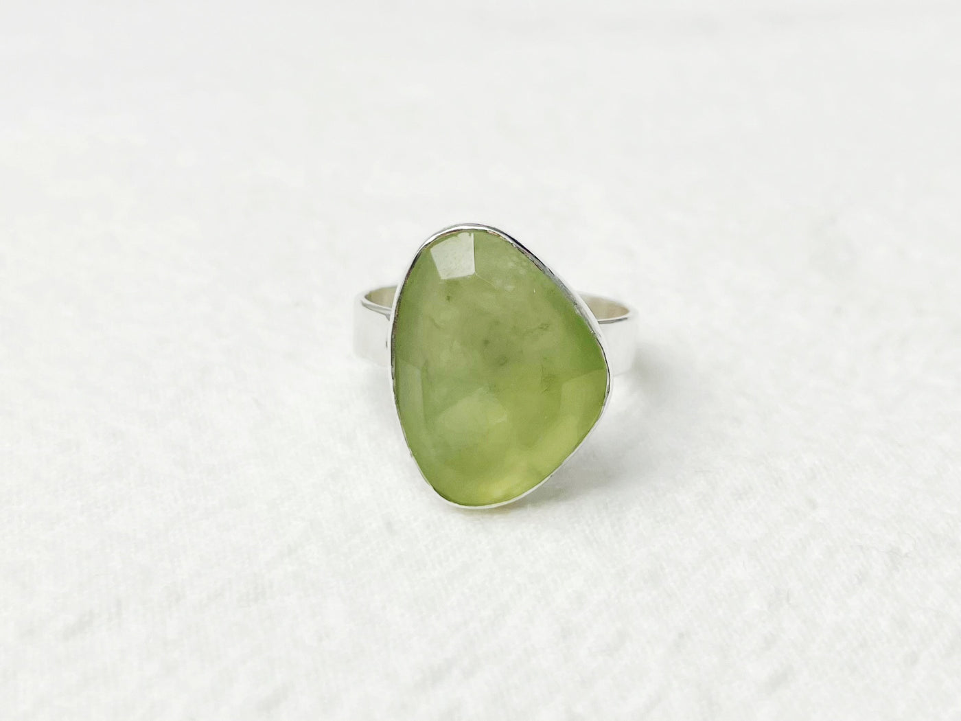 Green teardrop-shaped ring on a white textured background