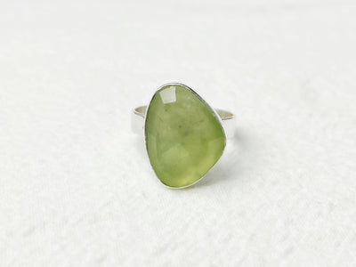 Green teardrop-shaped ring on a white textured background