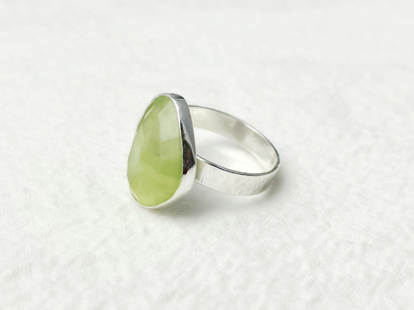 Silver ring with a green stone on a white background