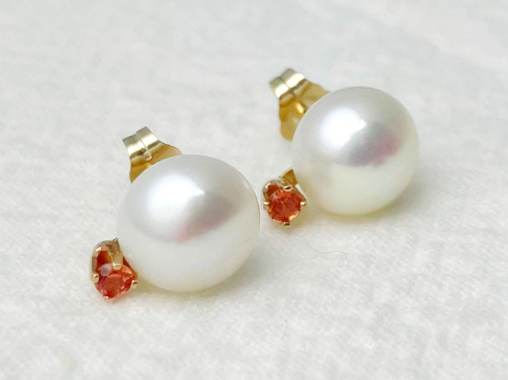 Pair of pearl earrings with gold and red accents on a white background