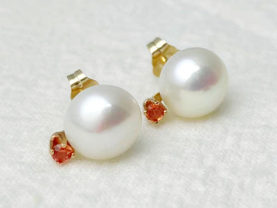 Pair of pearl earrings with gold and red accents on a white background