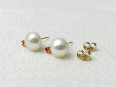 Pearl earrings with gold and orange accents on a white background