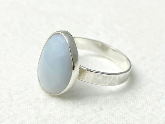 Silver ring with a light blue stone on a white background
