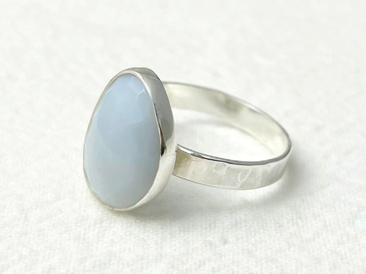 Silver ring with a light blue stone on a white background