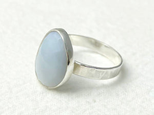 Silver ring with a light blue stone on a white background