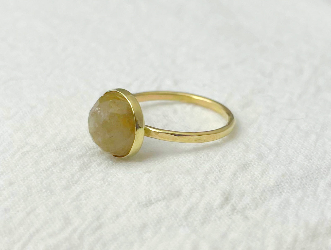 Gold ring with a round stone on a white textured background