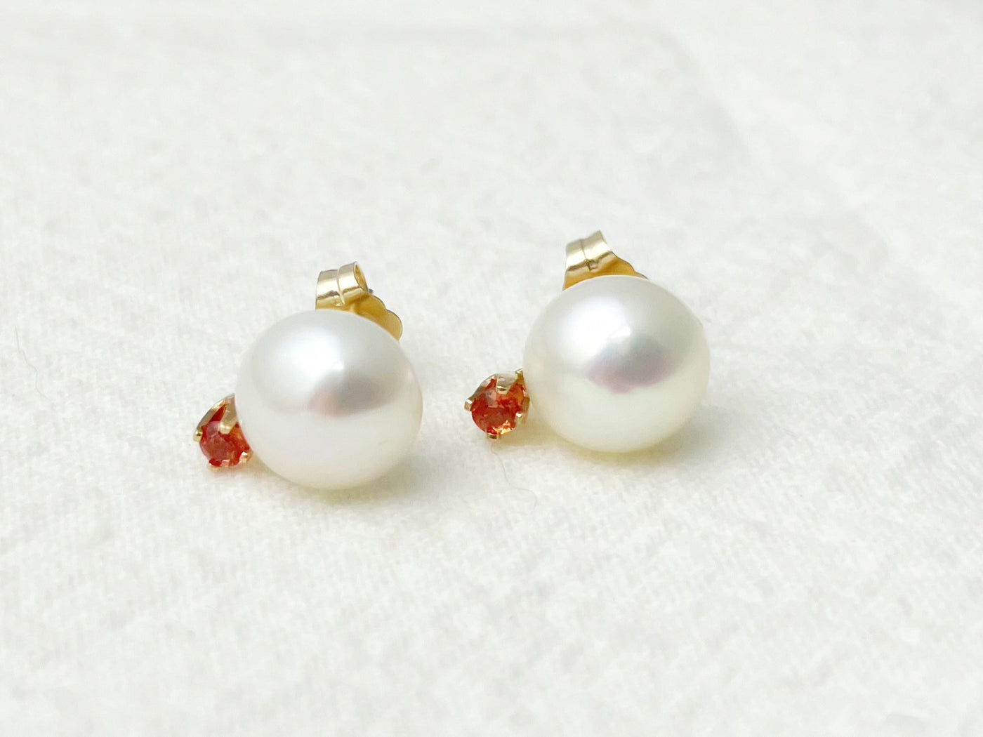 Pearl earrings with red gemstones on a white background