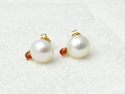 Pearl earrings with red gemstones on a white background
