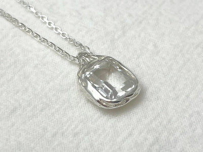 Silver pendant necklace on a white textured background