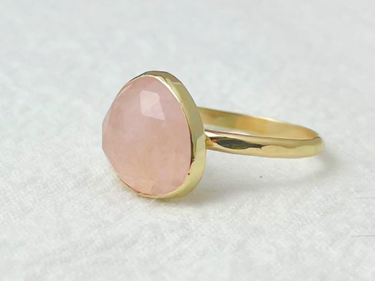 Gold ring with a pink stone on a white background