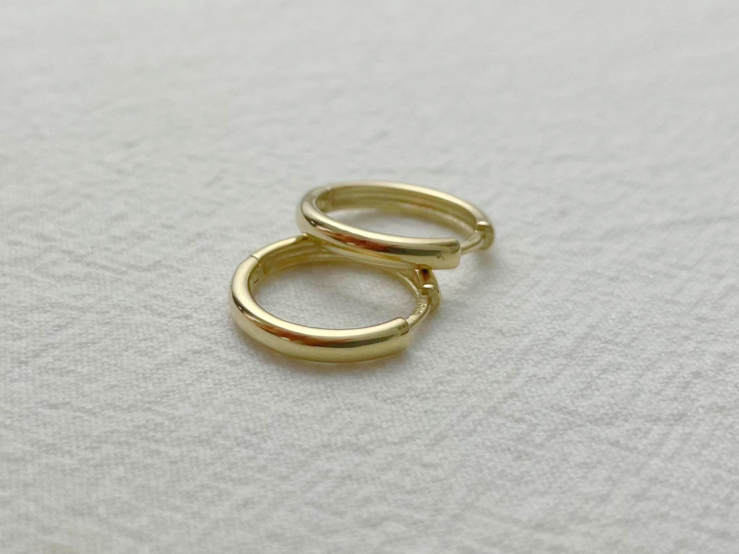 Classic yellow gold hoops, 16mm in diameter and 2.5mm thick, styled flat for detail view
