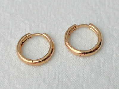 Pair of gold hoop earrings on a light gray background